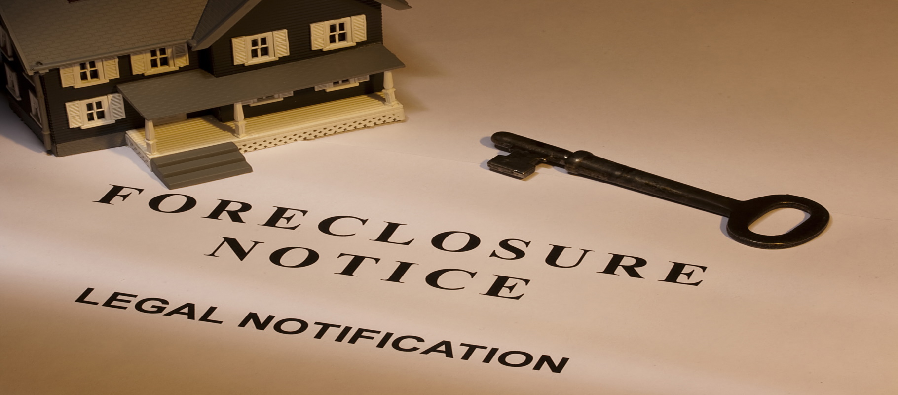 A key laying next to a house model and a foreclosure notice.- Meredith Law Firm, LLC., Foreclosure Attorneys - North Charleston, SC