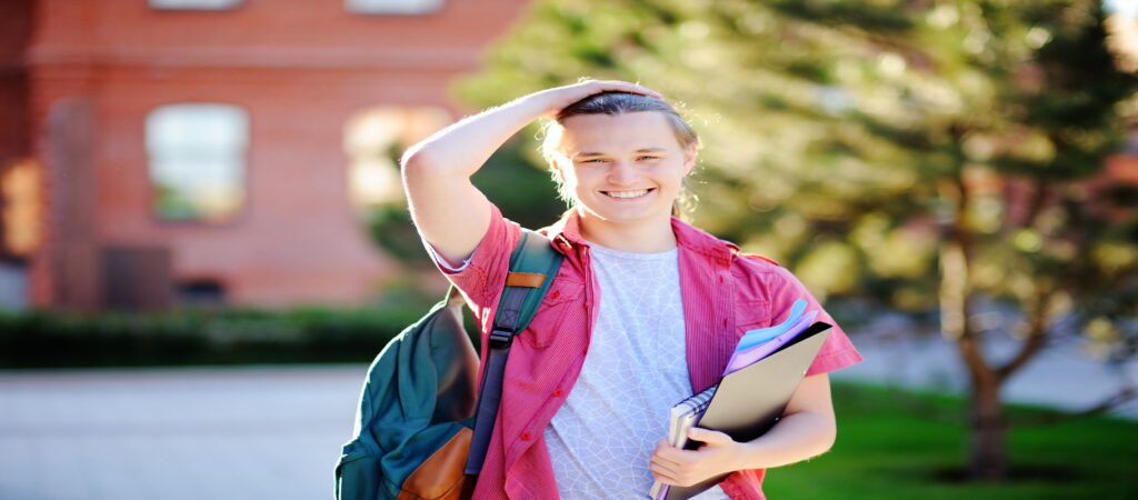 The smiling student, is standing on the college campus, with her right hand on her head and hold her notebooks with the left arm, Meredith Law Firm, Student Loan Debt, Columbia, S.C.