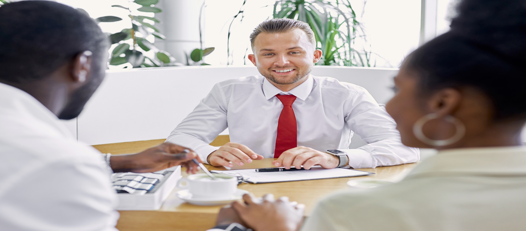 Three people are sitting at a table. A man and women are holding hands, while the man is stirring his coffee., Meredith Law Firm, Bankruptcy Lawyers, North Charleston, S.C.