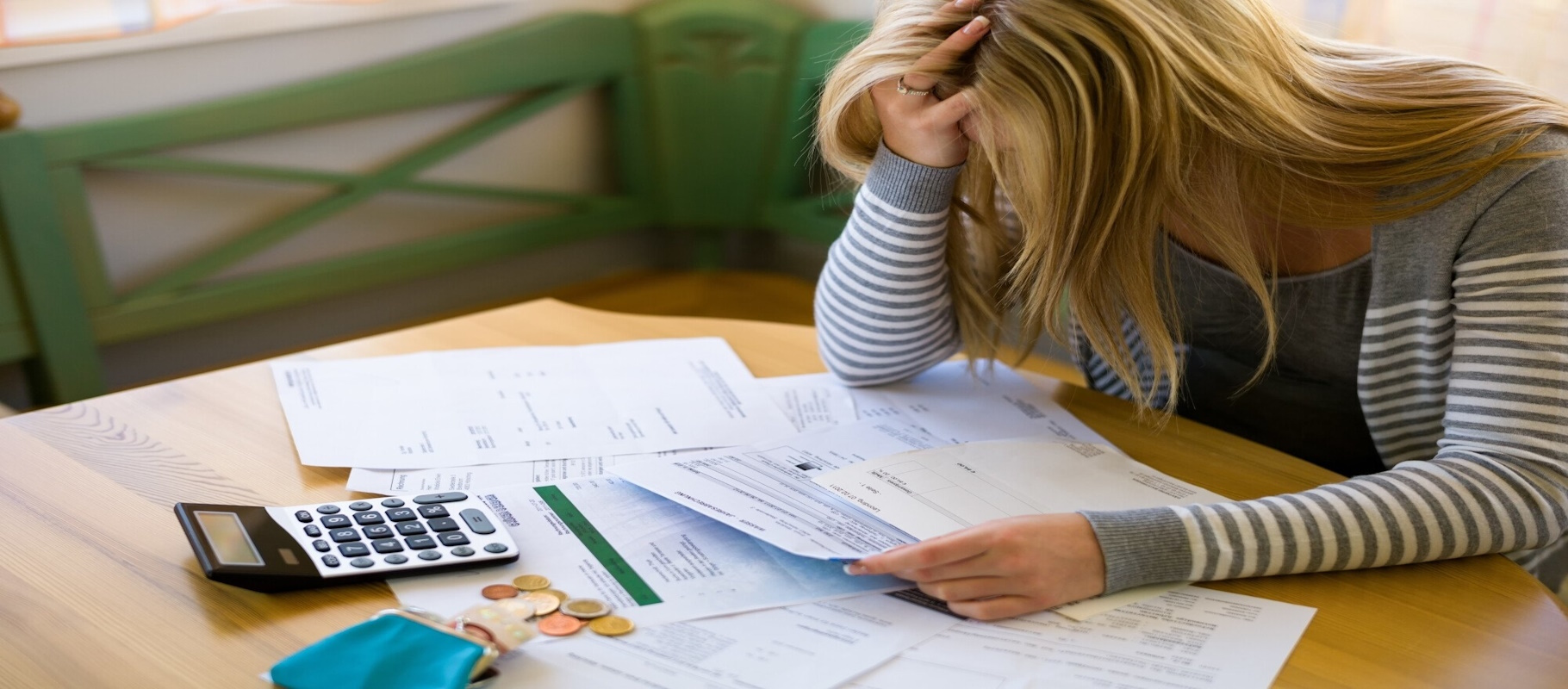A Woman is sitting at a table with papers spread acroos, calculator and pennies, 9 Signs You Need to File Chapter 7 Bankruptcy, Meredith Law Firm, Chapter 7 Bankruptcy Lawyers, Columbia, SC
